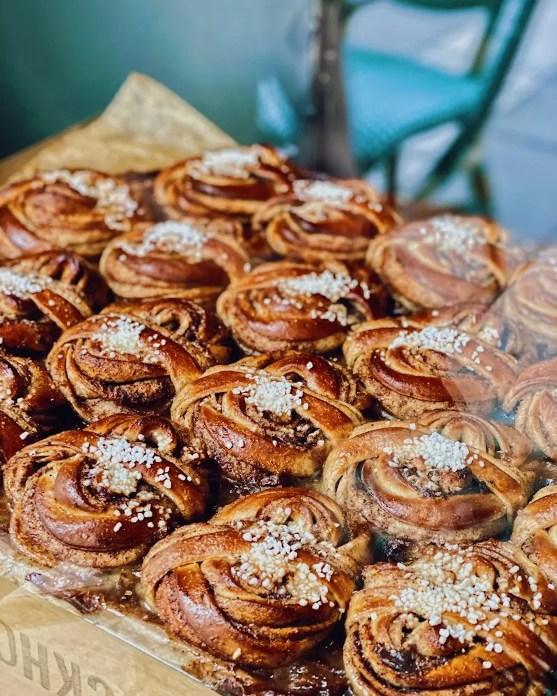 Nygräddade kanelbullar med pärlsocker på en plåt.